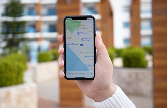 Man hand holding iPhone 11 with Apple map on screen