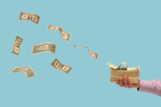 Money flying off stack of bills in man's hand